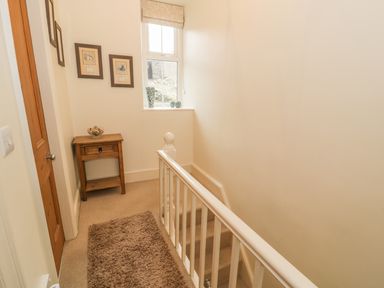 A hallway with a wooden door a small wooden table pictures on the wall a window and a staircase at Manod View in Blaenau Ffestiniog