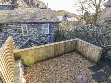 A small gravel yard with wooden fencing next to a stone house at Manod View in Blaenau Ffestiniog