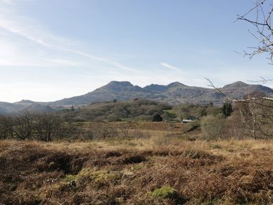 A rural landscape with hills and sparse trees under a blue sky at Manod View in Blaenau Ffestiniog