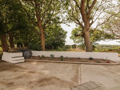 An outdoor area with a concrete surface a low white wall with plants and trees at Newtown East near Kilkee County Clare