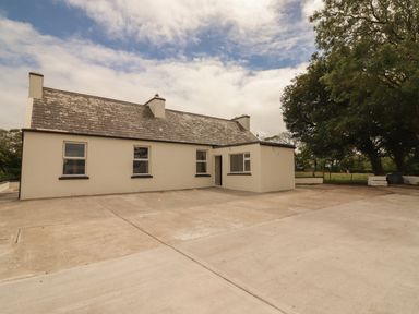A single story house with a concrete driveway and trees nearby at Newtown East in Newtown East near Kilkee County Clare