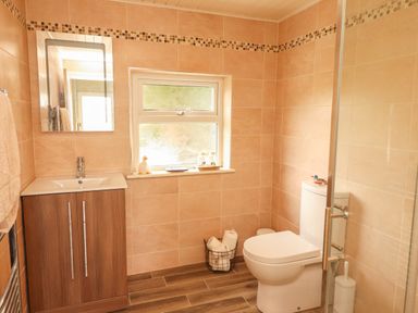 A bathroom with a sink cabinet mirror window toilet and a wire basket with toilet paper at Newtown East near Kilkee County Clare