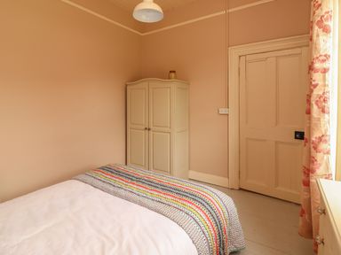 A bedroom with a bed a wardrobe a door and floral curtains at Newtown East near Kilkee County Clare
