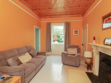 A sitting room with a sofa and armchair near a window and fireplace at Newtown East near Kilkee County Clare