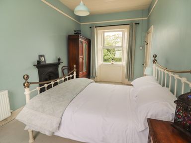 A bedroom with a bed a wardrobe a fireplace and a window at Newtown East near Kilkee County Clare