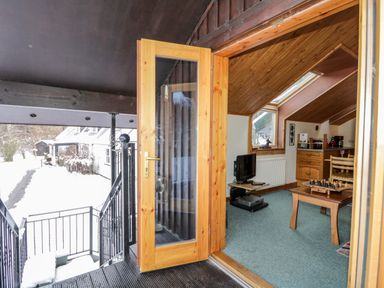 A kitchen and living room with a television chessboard and wooden furniture at Torbreck Chalet in Kincraig