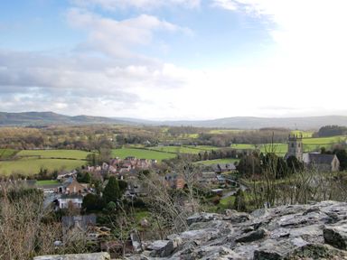 A village with houses and a church surrounded by fields and hills in the background at The Boars Head Pub in Bishops Castle