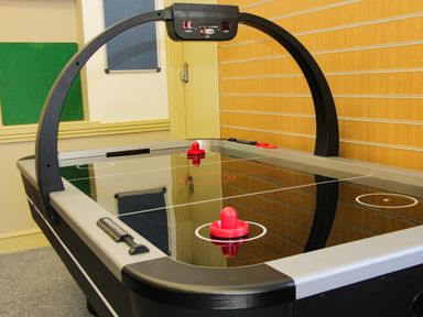An air hockey table with two red strikers in a room with wooden paneling on the wall at The Boars Head Pub in Bishop's Castle