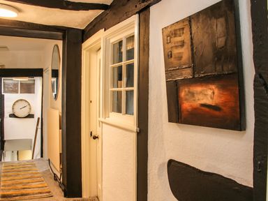 A hallway with a striped rug a round mirror a wall clock and abstract wall art at The Boars Head Pub in Bishops Castle