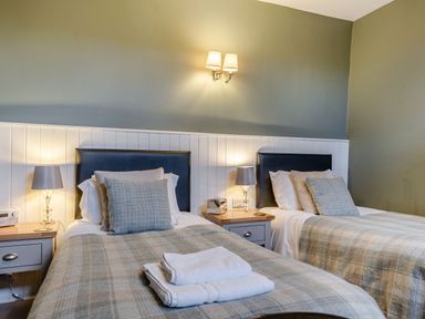 A bedroom with two single beds with pillows and lamps on bedside tables at The Boars Head Pub in Bishops Castle