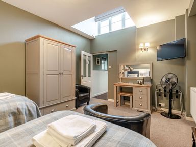 A bedroom with two beds a wardrobe a dressing table and a television at The Boars Head Pub in Bishops Castle