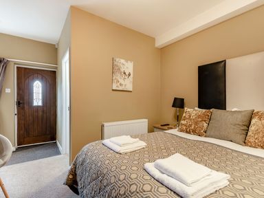 A bedroom with a bed towels on top a bedside table with a lamp and a wooden door at The Boars Head Pub in Bishop's Castle