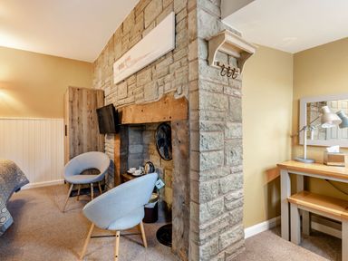 A room with two chairs and a television near a stone fireplace and a desk with lamps and a mirror at The Boars Head Pub in Bishops Castle