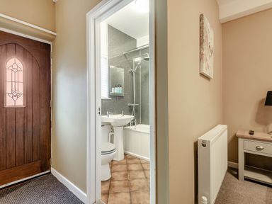 A bathroom with a toilet sink and bathtub visible through a doorway beside a wooden door and radiator at The Boars Head Pub in Bishops Castle