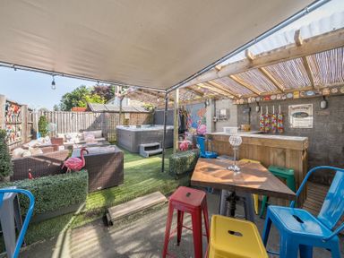 An outdoor seating area with colorful chairs tables a wooden bar and a hot tub at The Boars Head Pub in Bishops Castle