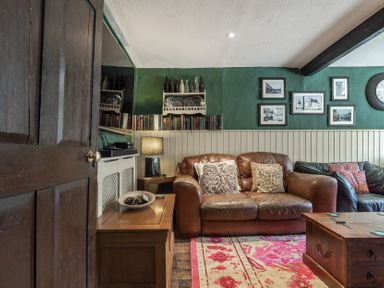 A living room with a brown leather couch pillows wooden furniture and framed pictures on the wall at The Boars Head Pub in Bishops Castle