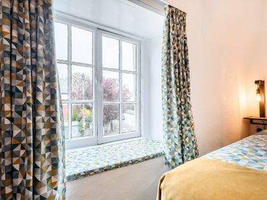 A bedroom with a window and patterned curtains at The Boars Head Pub in Bishop's Castle