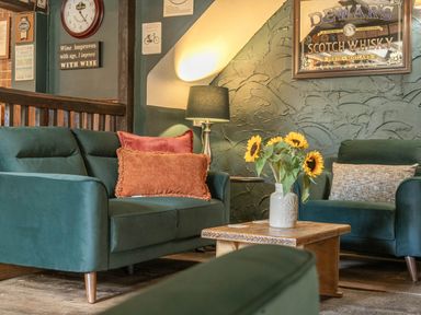 A living room featuring a sofa, armchair, and table at The Boars Head Pub in Bishop's Castle