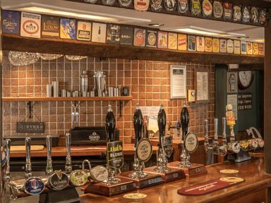 A bar counter with beer taps and shelves with glasses at The Boars Head Pub in Bishop's Castle