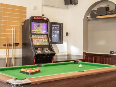 A game room with a pool table and gambling machine at The Boars Head Pub in Bishop's Castle