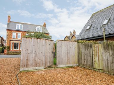 A gravel driveway with a wooden gate and fences near residential houses at Little Wash Cottage in Hunstanton
