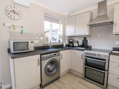A kitchen with a washing machine microwave oven coffee maker and kettle at Little Wash Cottage in Hunstanton