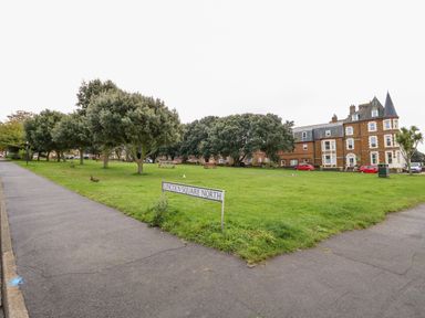 A green area with trees benches and a Lincoln Square North sign near a brick building in Hunstanton