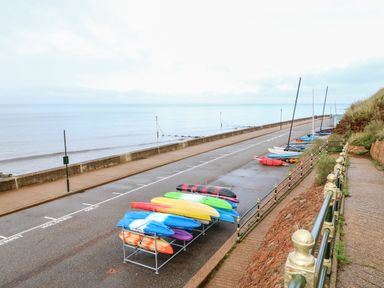 A row of kayaks and small sailboats next to a waterfront road with a sea wall at Little Wash Cottage in Hunstanton