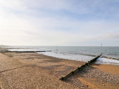 A beach with wooden groynes extending into the sea and a cloudy sky at Little Wash Cottage in Hunstanton