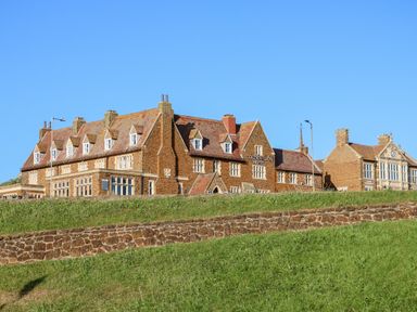 A stone hotel building with multiple chimneys and windows on a grassy hill at Golden Lion Hotel in Hunstanton