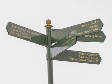 A green signpost with directions to local attractions and facilities