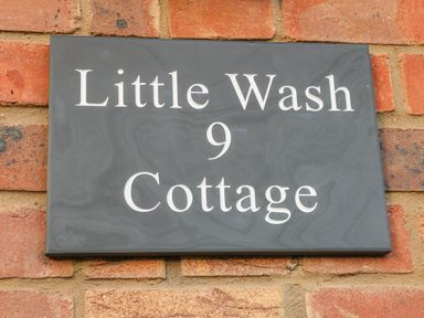 A house name plaque reading Little Wash 9 Cottage on a brick wall at Little Wash Cottage in Hunstanton