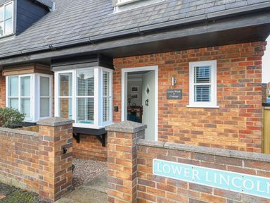 The front entrance of a brick house with a small garden area and a sign reading lower lincoln at Little Wash Cottage in Hunstanton