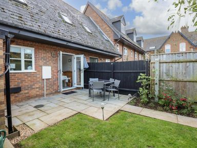 A small garden patio area with outdoor furniture and green grass at Little Wash Cottage in Hunstanton