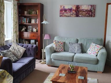 A living room with two sofas and a wooden bookshelf at Mimis Cottage in St Neot