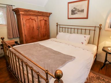 A bedroom with a metal bed frame wooden wardrobe and bedside table at Mary Rose Cottage in Cordal near Castleisland County Kerry