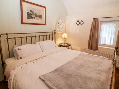 A bedroom with a bed a bedside table with a lamp a window and a picture on the wall at Mary Rose Cottage in Cordal near Castleisland County Kerry