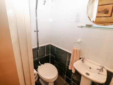 A small bathroom with a toilet a sink with separate taps and a towel hanging on the wall at Mary Rose Cottage Cordal near Castleisland County Kerry