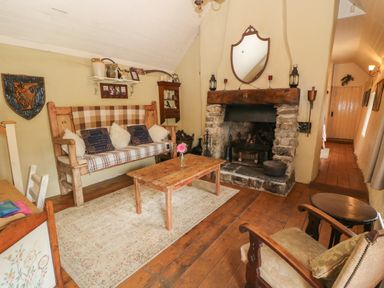 A living room with a stone fireplace wooden furniture and a beige rug at Mary Rose Cottage in Cordal near Castleisland County Kerry