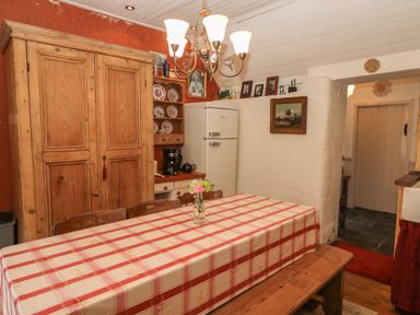 A kitchen with a wooden table covered with a red and white checkered tablecloth and a wooden bench at Mary Rose Cottage in Cordal near Castleisland County Kerry