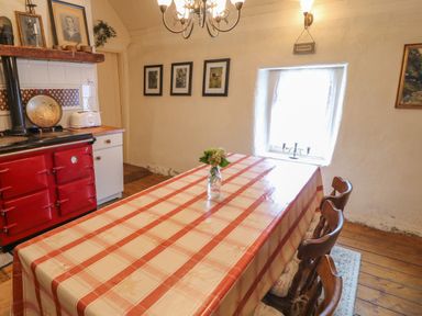 A dining room with a checkered tablecloth on a table and a red stove at Mary Rose Cottage Cordal near Castleisland County Kerry
