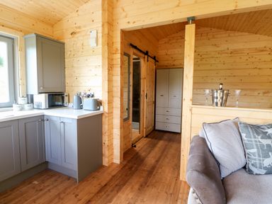A kitchen with grey cabinets and appliances next to a sitting area with a sofa at Badgers Sett in Winston near Staindrop
