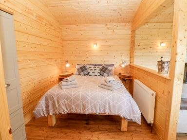 A wooden bedroom with a double bed two nightstands and a radiator at Badgers Sett in Winston near Staindrop