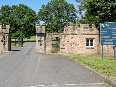 Stone entrance gate with iron gates and signboard at Raby Castle in Winston near Staindrop