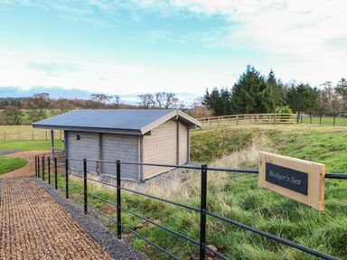 A small wooden building next to a black metal fence with a sign that says Badgers Sett in Winston near Staindrop