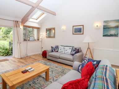 A living room with a sofa and coffee table at Tregona in Buckland Monachorum near Yelverton