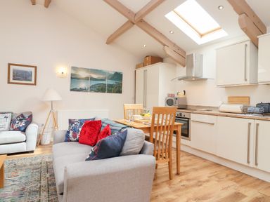 A living room with a dining table and kitchen area at Tregona in Buckland Monachorum near Yelverton