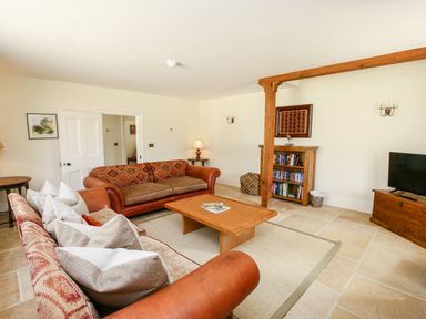 A living room with two sofas a wooden coffee table a bookshelf and a television at Shifford Manor Farm Shifford near Bampton Oxfordshire