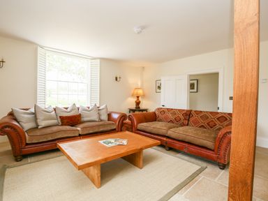 A living room with two leather sofas a wooden coffee table and a table lamp at Shifford Manor Farm in Shifford near Bampton Oxfordshire