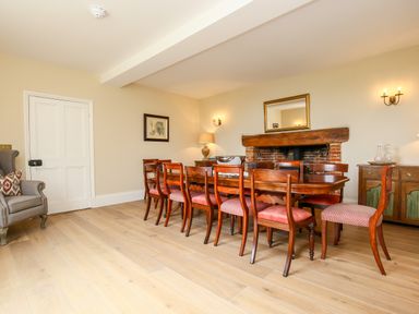 A dining room with wooden table and chairs a fireplace and an armchair at Shifford Manor Farm in Shifford near Bampton Oxfordshire